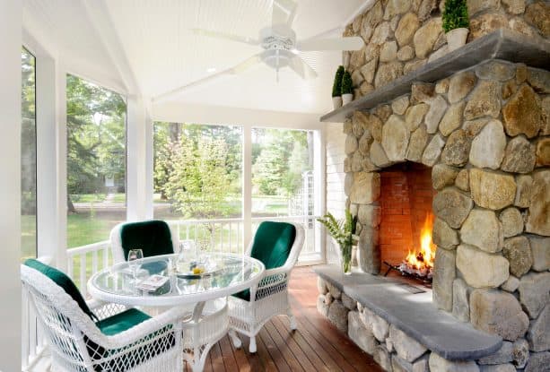 the pairing between white-themed screened porch and yellow stone fireplace