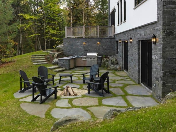 a roofless traditional walkout basement patio with black outdoor chairs, fire pit, and a grilling station