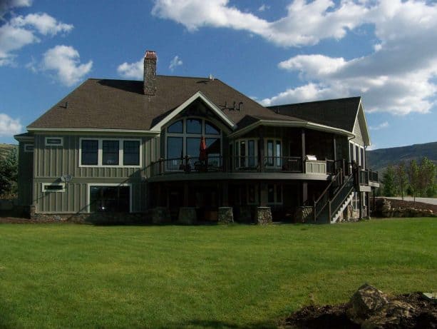 a rustic greyish-green mountain house with green views around it