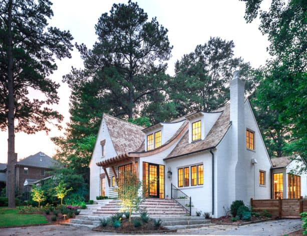 white-painted brick home with unique single gable roof and red brick accents