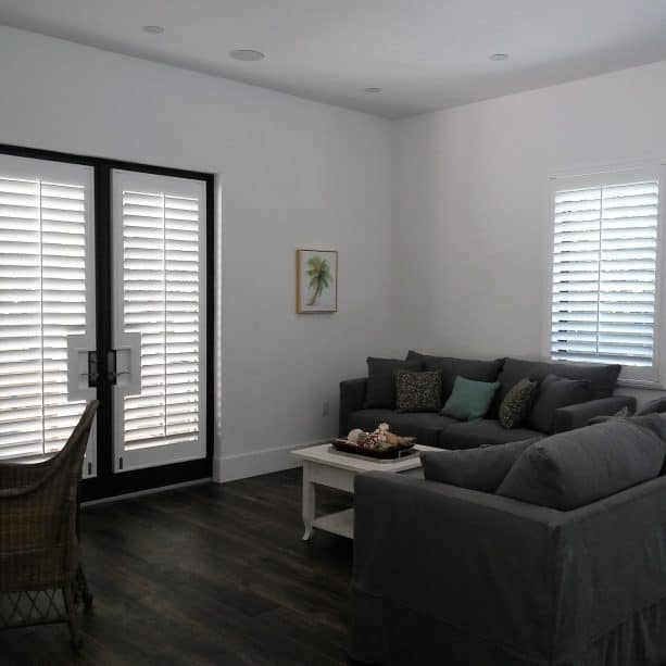black French doors covered by white plantation shutters
