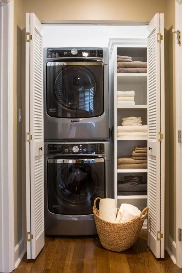 laundry closet with folded louvered doors at the end of a hallway
