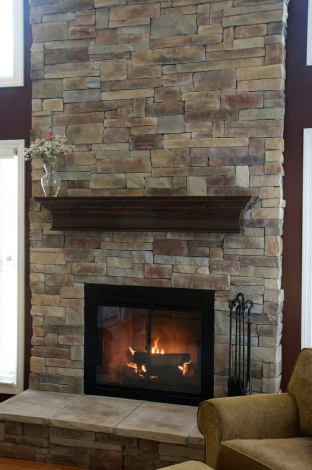 after makeover tall floor to ceiling fireplace with black insert with glass cover and raised hearth with neutral tone tiles