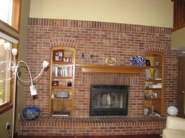 before makeover floor to ceiling brick fireplace with mantel shelf, built-in enclosing shelves and long raised hearth