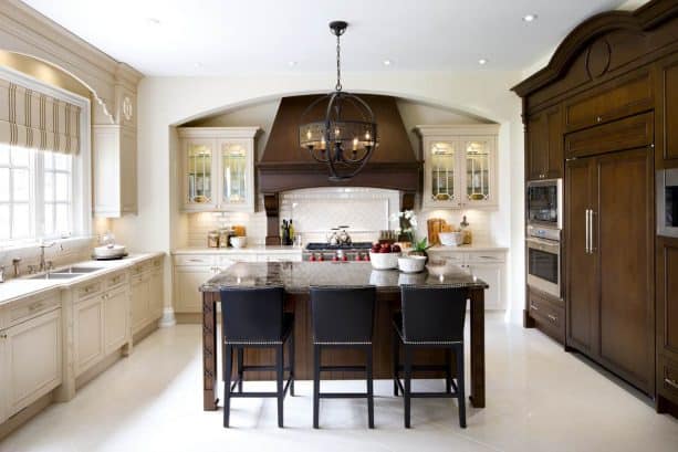 off-white kitchen cabinets paired with dark wood custom cabinets, range hood, and an island