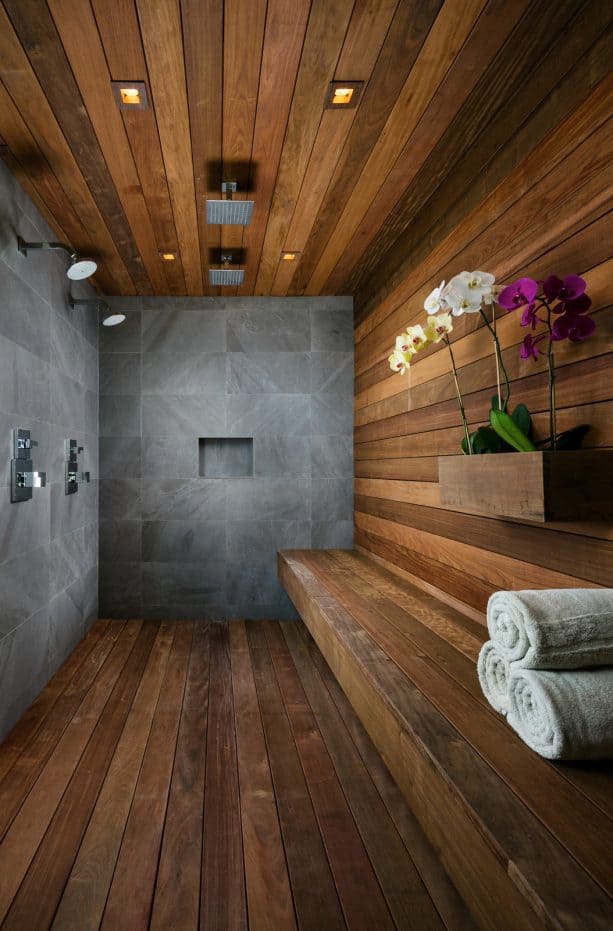 a spa-inspired bathroom that looks cozy with natural stone walls and dark hardwood floor