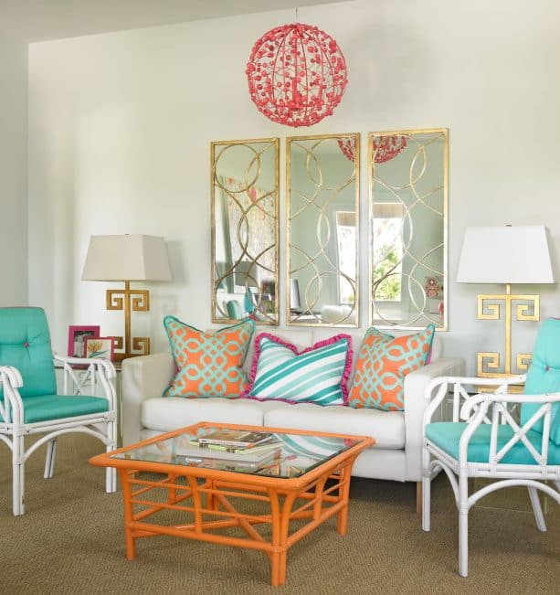 a contemporary living room with turquoise chairs and gold mirror