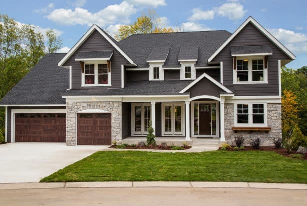 a transitional home exterior design with dark grey walls, stone walls, and white trim
