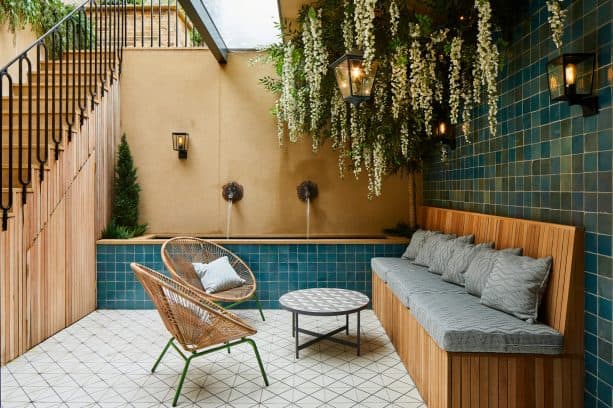 Mediterranean walkout basement patio with blue tiles, hanging plants, and water feature