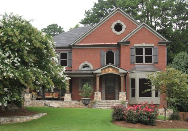 a red brick house with grey roof and grey shutters