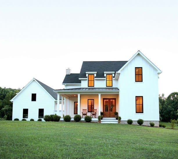 a white farmhouse with charcoal grey roof shingles