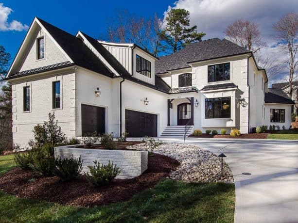 a white transitional house with black roof