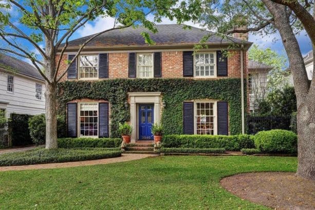 navy front door paired with black shutters in red brick home exterior
