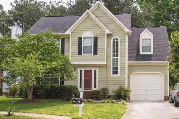 a traditional exterior with yellowish sage green paint on the wall siding