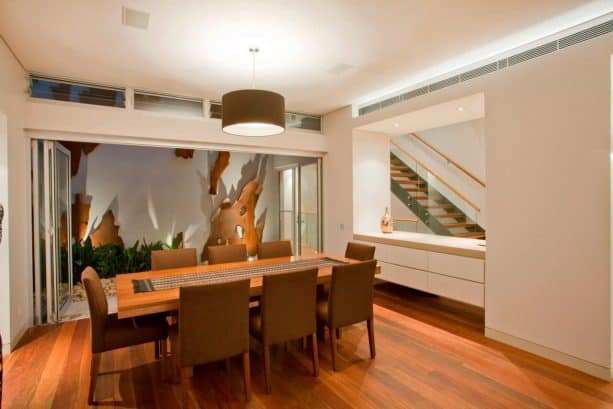 a dining room and a hallway separated with a large glass window