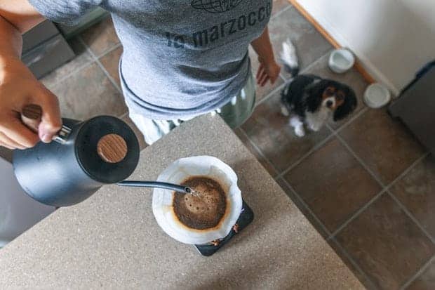 Woman pouring water from a gooseneck kettle into a pour over cone