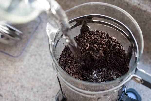 Pouring water onto ground beans in a French press