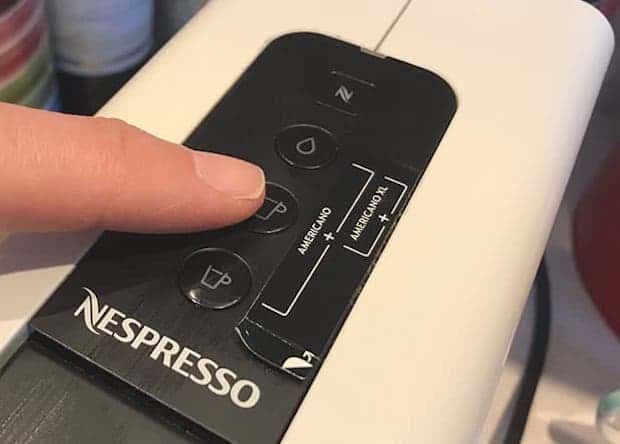 Finger on the lungo button of a Nespresso machine