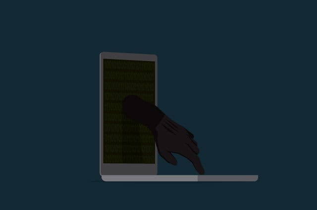 what-is-cybercrime A sinister hand emerges from a laptop screen.