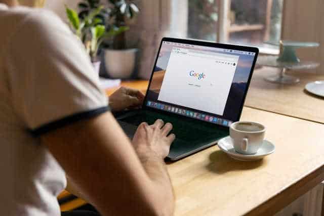 Photo of someone sitting at a desk typing into Google on a laptop. Photo by Firmbee on Unsplash