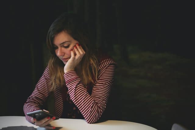 A woman in a striped top reading on her smartphone. Photo by Kev Costello on Unsplash