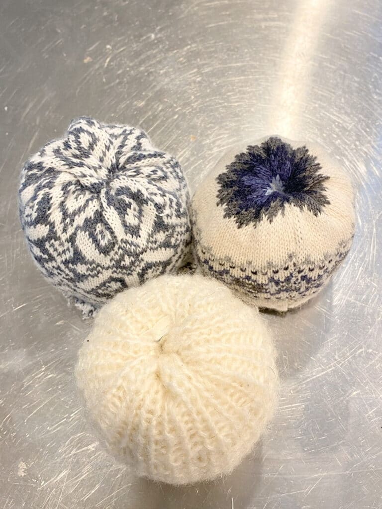 Here are all 3 DIY sweater pumpkins after the sweater material has been cut and poked into the holes of each pumpkin.
