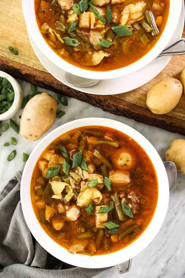 Hamburger soup image overhead picture with two bowls and potatoes and green onions