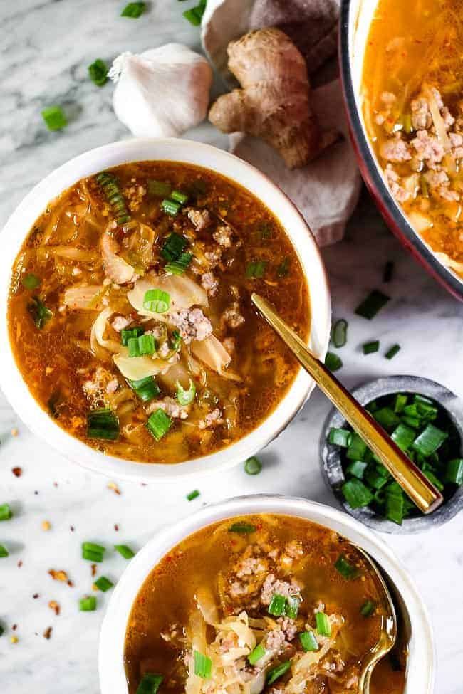 Bowls of kimchi soup with ground pork and topped with chopped green onion.