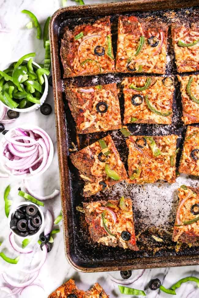 Cut up Meatza in sheet pan with toppings on side vertical image