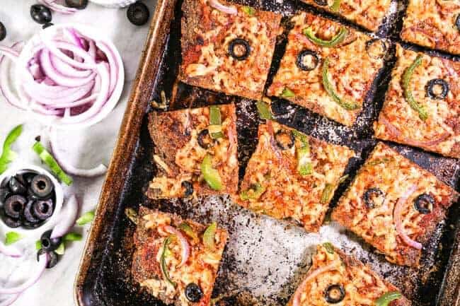 Cut up Meatza in sheet pan with toppings on side horizontal image