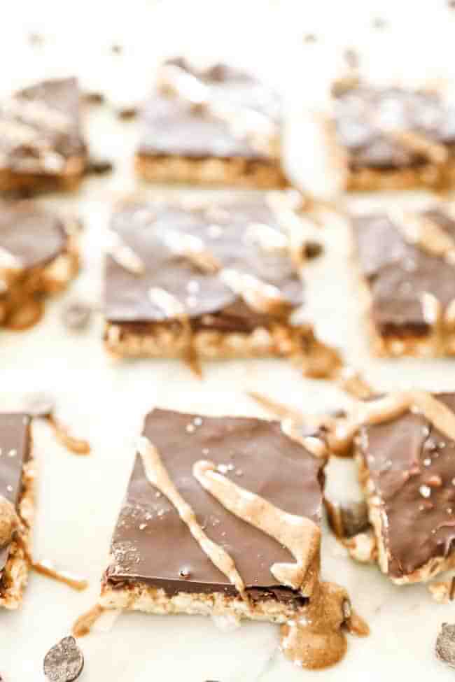 Angled shot of peanut butter bars with nut butter drizzle and sea salt on top.