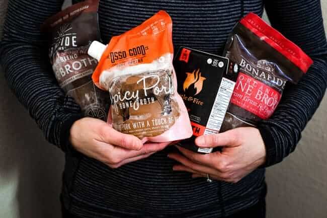 Holding several different kinds of bone broth and a post about where to buy bone broth.