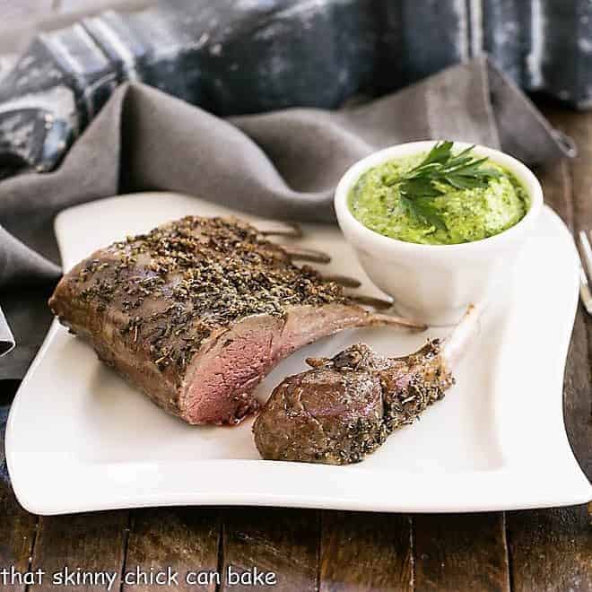 Herb Crusted Rack of Lamb with Parsley Pesto - an elegant, delicious entree for company, Easter dinner or whenever tender spring lamb is available! Herb Crusted Rack of Lamb on a white dinner plate with a bowl of parsley pesto