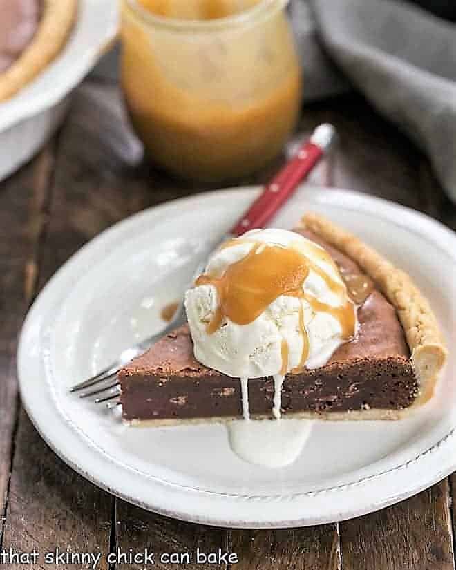 Fudgy Brownie Pie - Rich brownie filling studded with chocolate chips and baked in a flaky pastry shell! A slice of Fudgy Brownie Pie topped with ice cream and caramel sauce