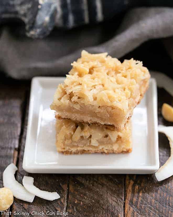 Coconut Macadamia Nut Bars - Coconut Lovers' dream bars! With a shortbread crust and a chewy coconut topping, they'll rock your taste buds!! Coconut Macadamia Nut Bars stacked on a square white plate