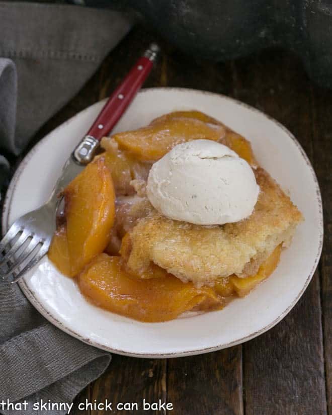 Easy Peach Cobbler - A timeless, classic fruit dessert that's perfect with ripe summer peaches Overhead view of a scoop of easy peach cobbler on a white plate with scoop of vanilla ice cream