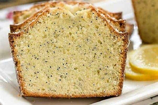 Glazed Poppy Seed Bread slices on a white tray with lemon slices