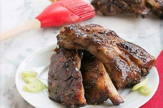 Asian Baby Back Ribs on a white plate with a red basting brush