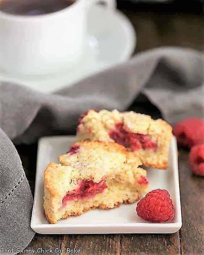Raspberry Cream Scones - terrific, tender scones studded with fresh raspberries Raspberry Cream Scones broken in half on a white plate with a raspberry garnish