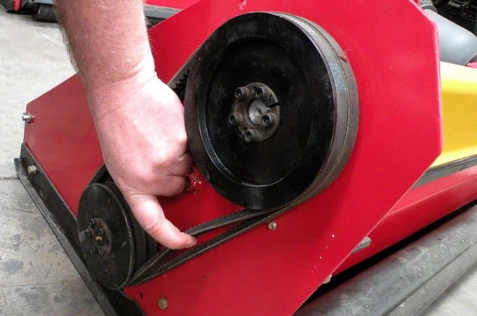 Check for tension by pulling the belt at it's midpoint between the pulleys. The tension on this flail mower belt is too loose.