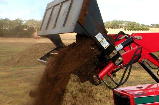 Opening the 4-in-1 bucket to drop soil.