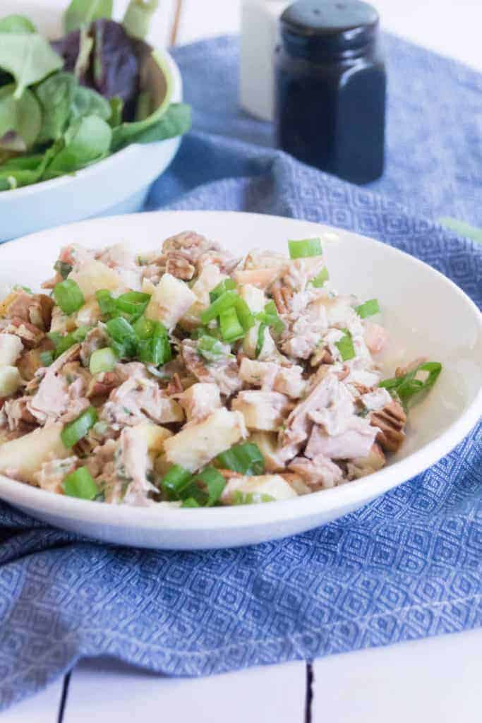Waldorf Tuna Salad in a white bowl, on top of a blue tea towel.