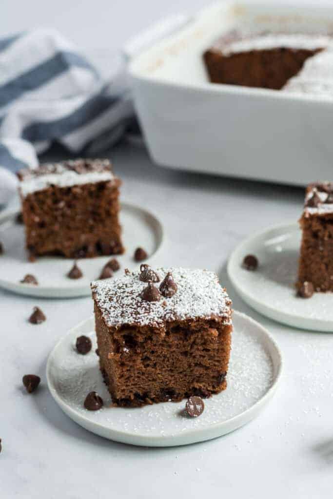 chocolate chip cake with white confectioners sugar and chocolate chips on top on white plates