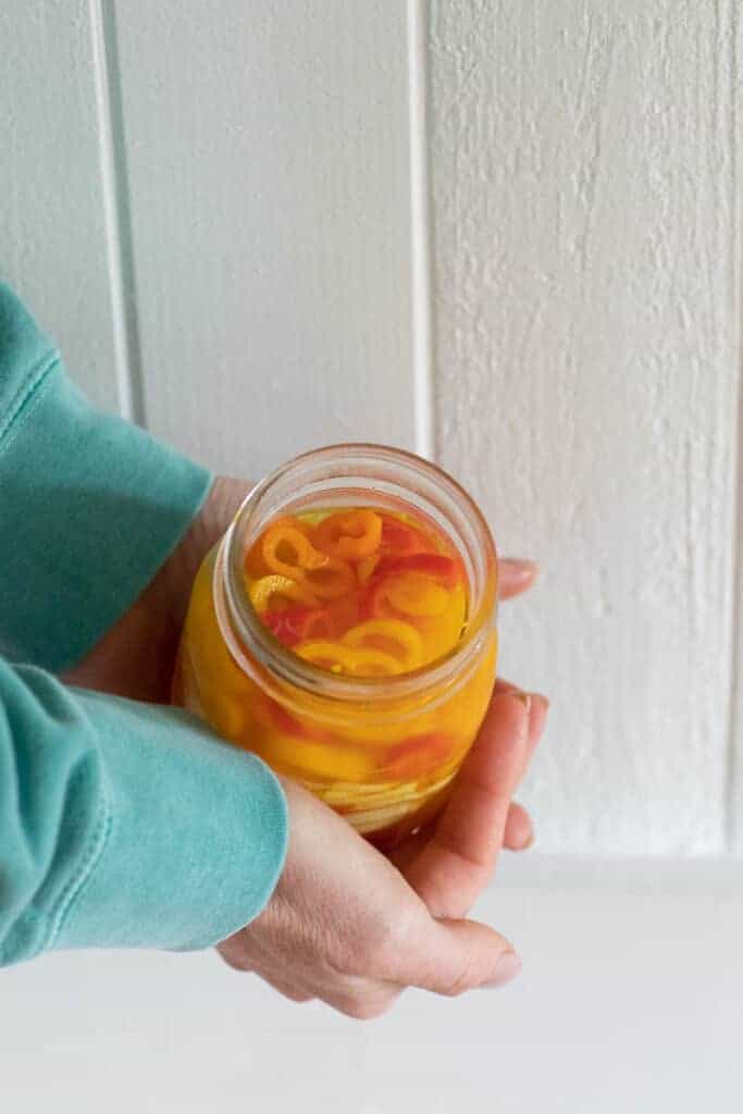 person holding jar of pickled sweet peppers