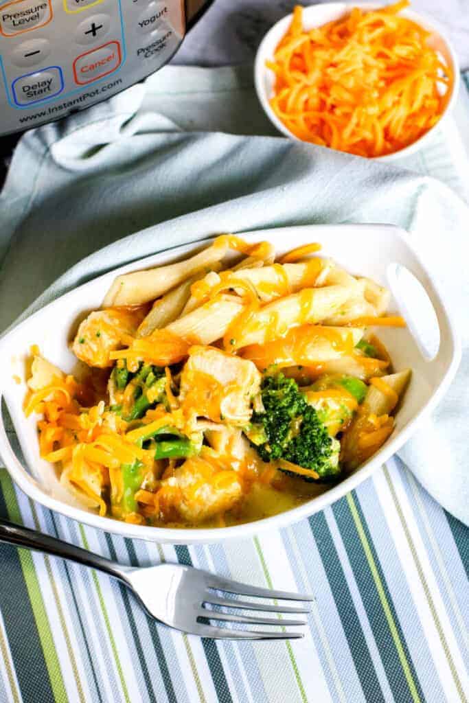 instant pot on table with shredded cheese and chicken and broccoli pasta