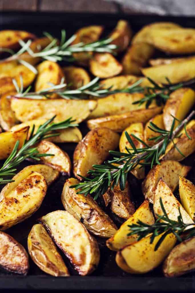 Baked Potato Wedges Baked Potato Wedges with fresh rosemary on a sheet pan