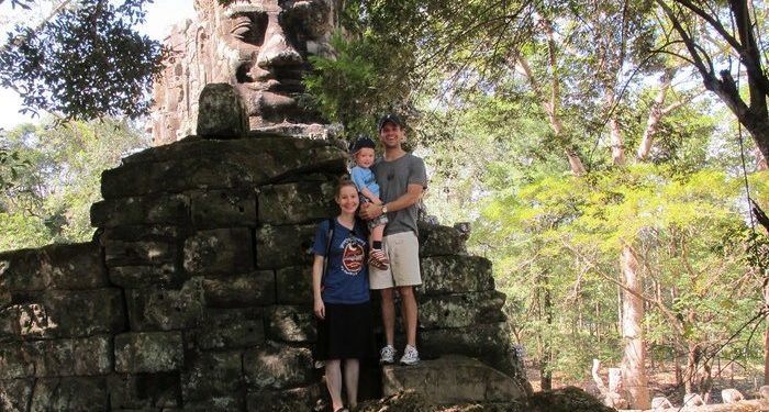 The family at the north gate of angkor wat, siem reap's most famous ruined temple.