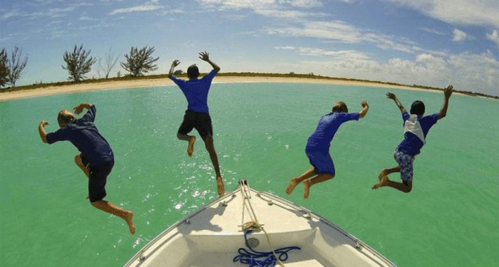4 boys jumping off a boat in turks & caicos