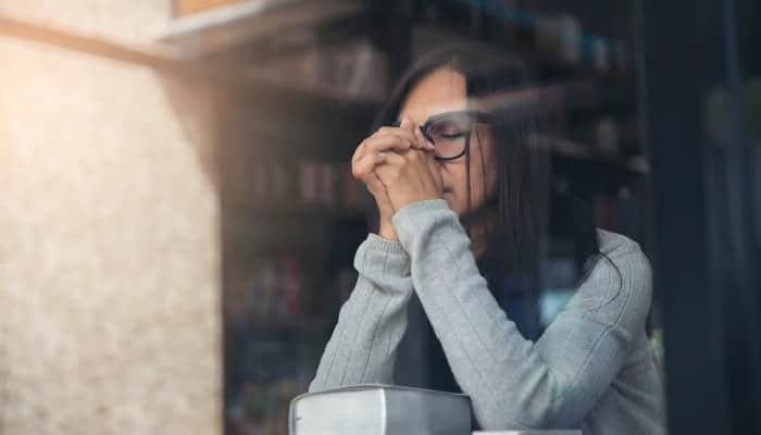 woman with hands folded on Bible praying