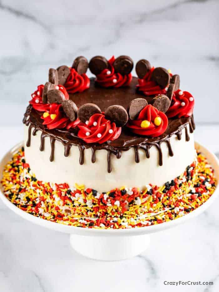 A cake decorated with red, yellow and black sprinkles and frosting.